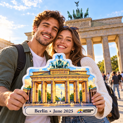 Travel couple holding a personalized Brandenburg Gate pillow in front of the Brandenburg Gate in Berlin